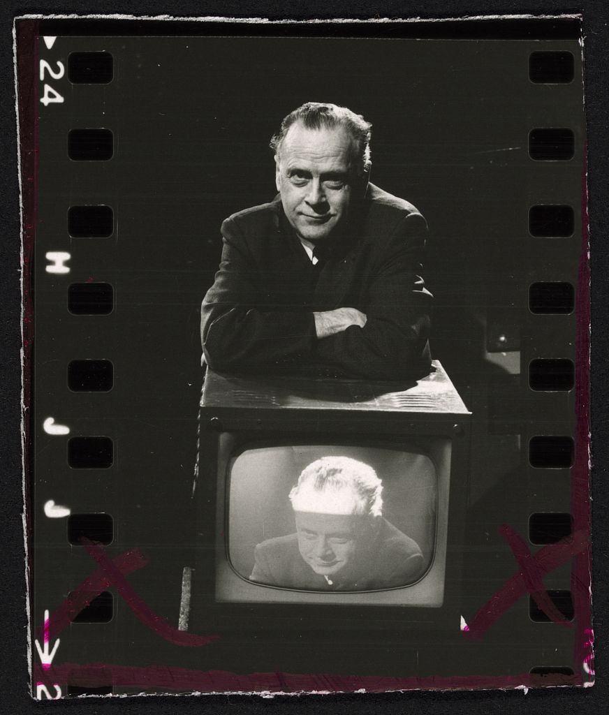 Marshall McLuhan leaning on a television set showing his own image, ca. 1967